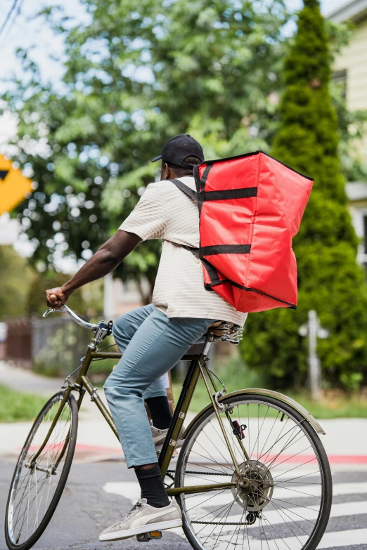 a man on a bicycle with a red bag strapped to it