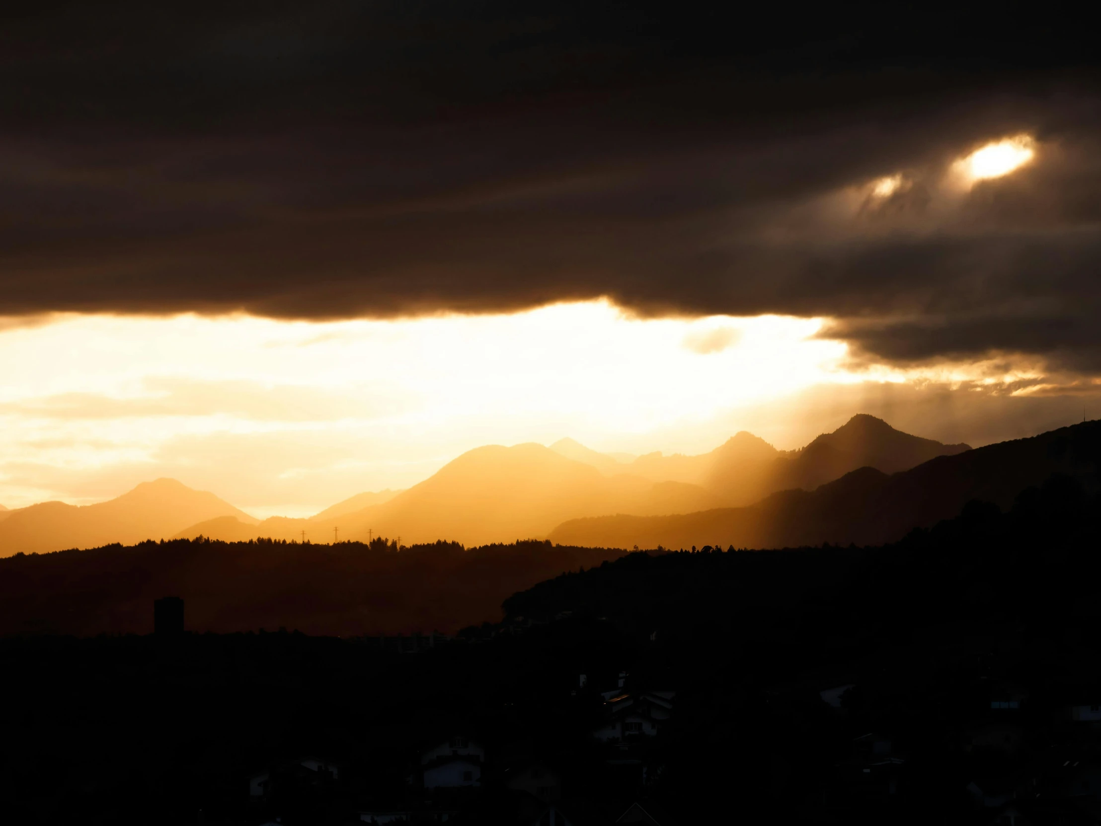 the sun is shining behind some mountains and houses