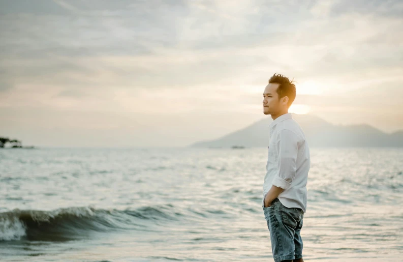 a man standing in the ocean at sunset