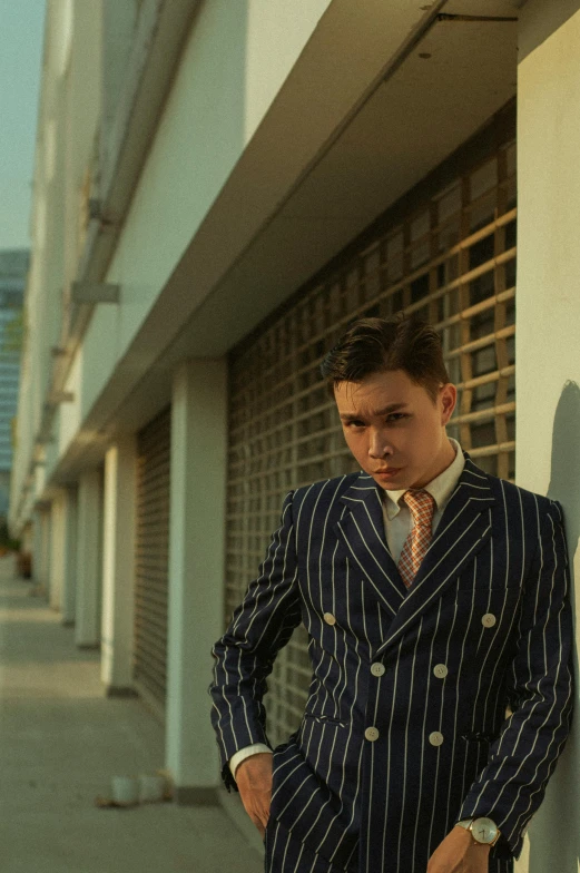 a man in suit and tie leaning against a wall