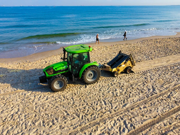 a tractor pulling a trailer down the sand at the beach