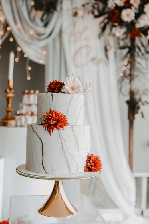 a white, marble cake with two different flowers on top