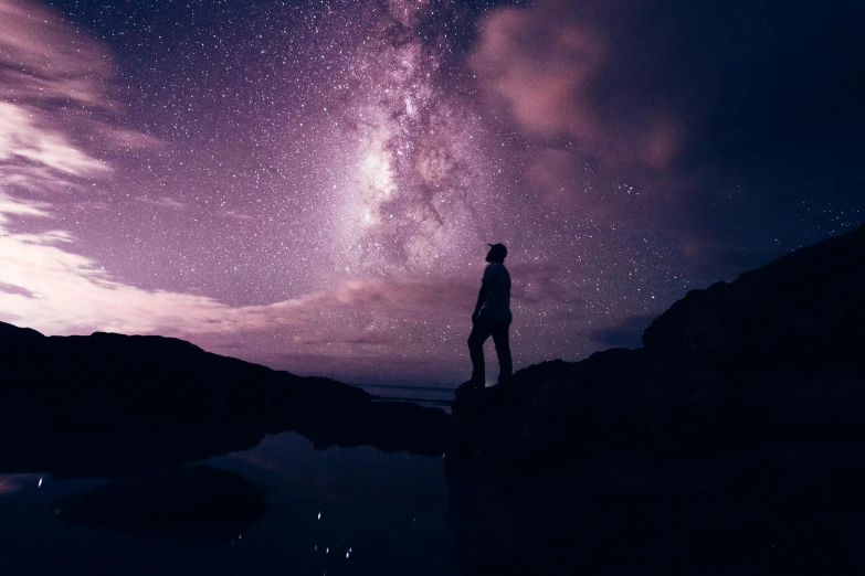 a person is standing on top of a mountain watching the stars