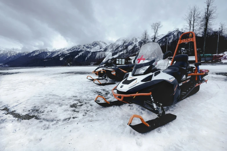 two snowmobiles parked next to each other on the snow