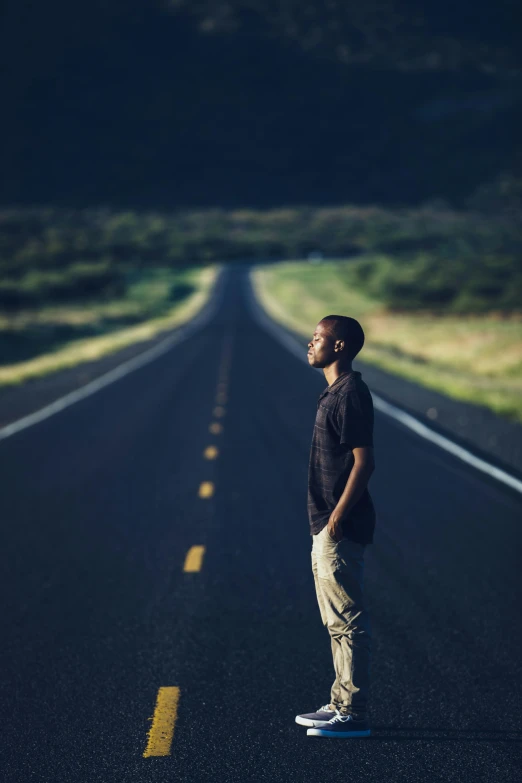 a young man on a skateboard standing alone in the middle of the road