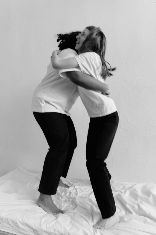 two women are hugging on the bed with their hands in each others'faces