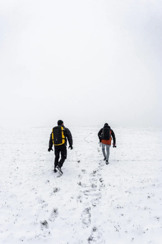 two skiers walking in the snow with jackets on