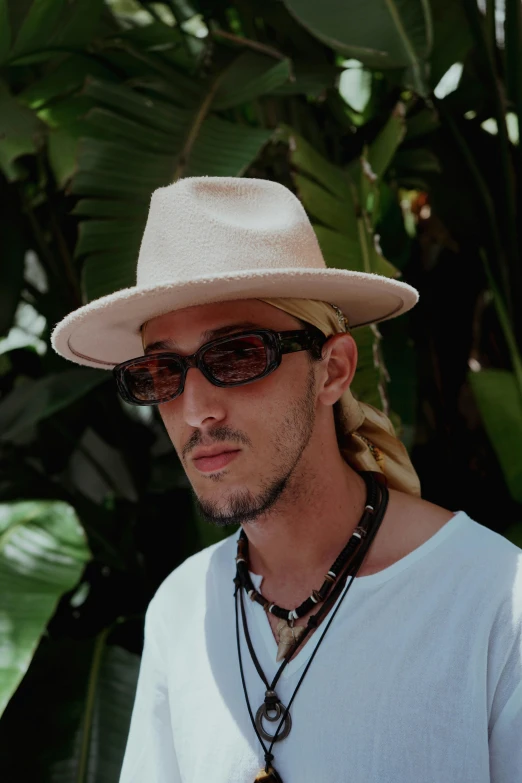 a man in a hat wearing sunglasses and beads