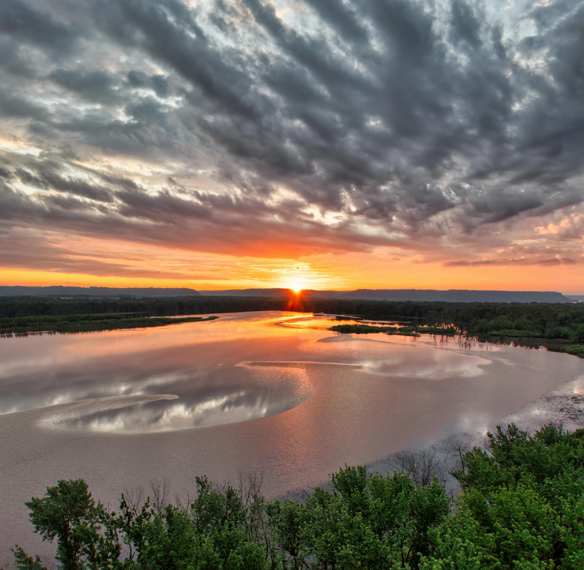 a sunrise over a lake with clouds over it