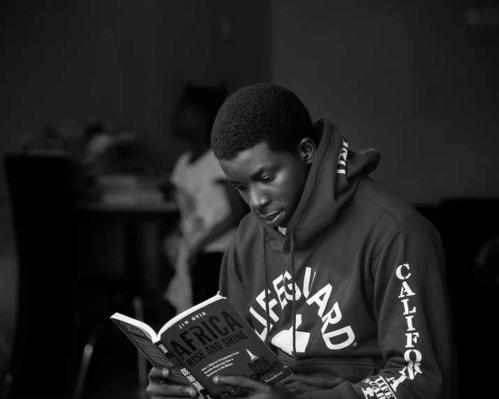 a young man reading a book while sitting in a chair