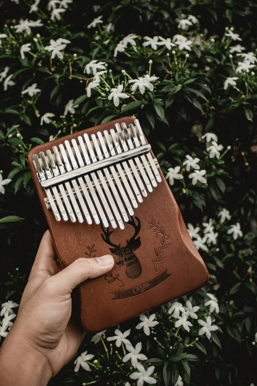 a person holding an instrument in front of flowers