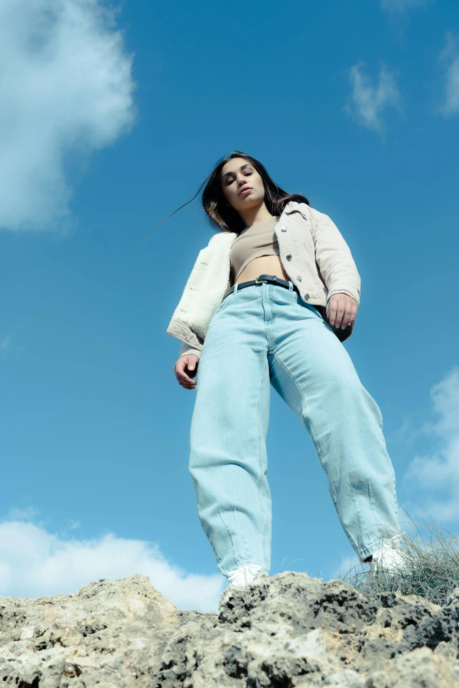 a woman standing on rocks with her arms crossed