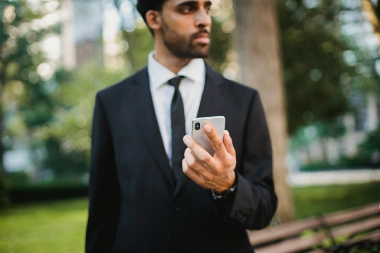 a man wearing a suit, necktie, and holding a cell phone