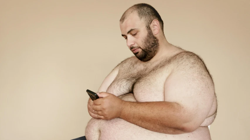 a man with a hairy body using his cell phone