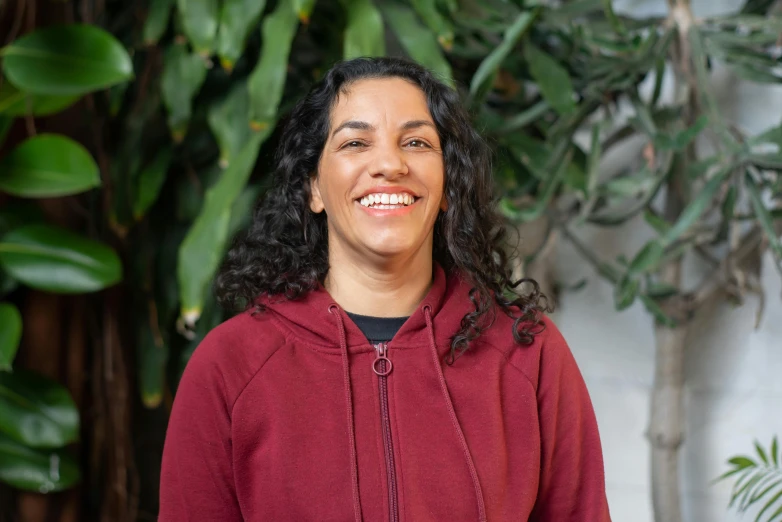 a person is standing smiling in front of some plants