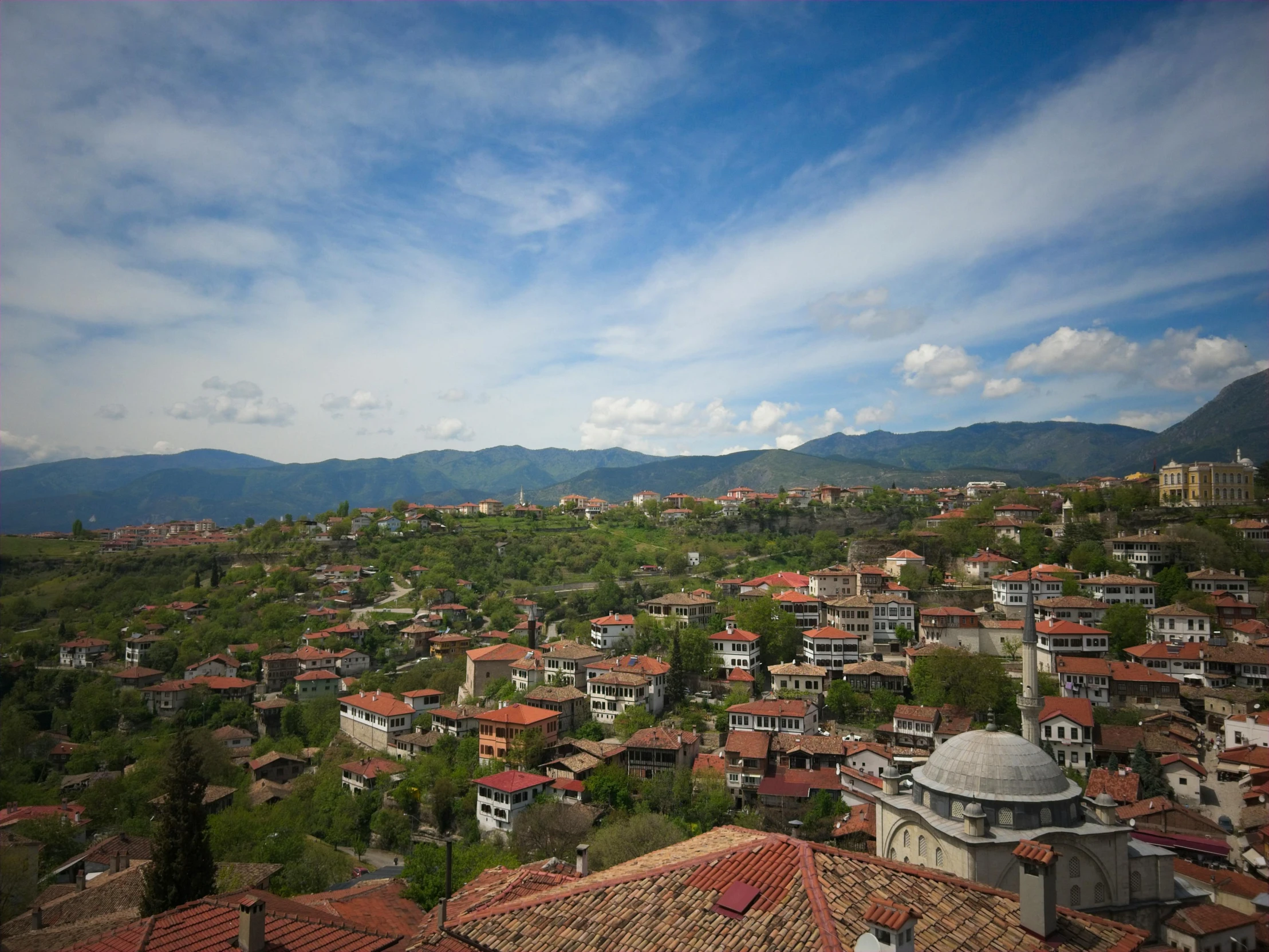 a city with lots of roofs and houses in front of mountains