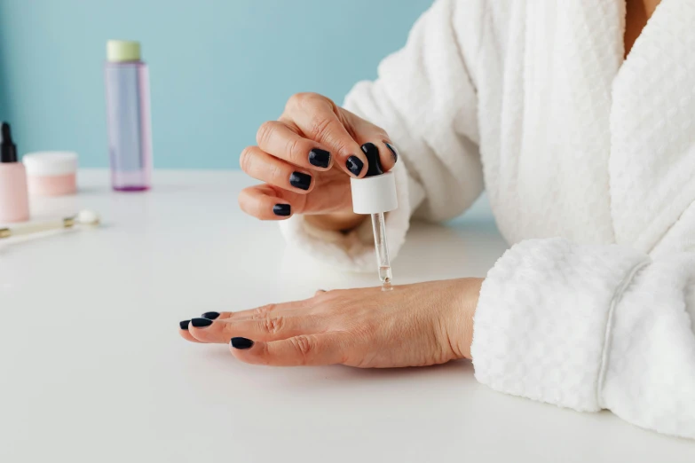 a woman is applying a nail polish on her nails