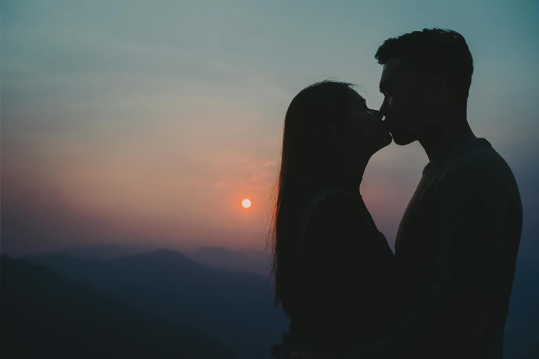 a man and woman kissing in the sunset