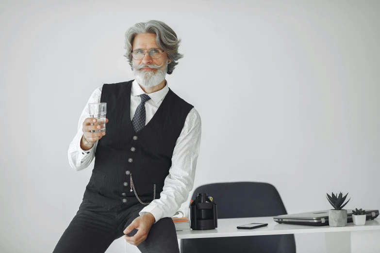 an older man in a vest, tie and shirt holding a glass