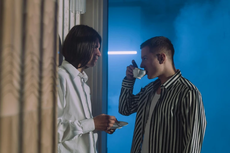 two young men standing in a room drinking out of cups