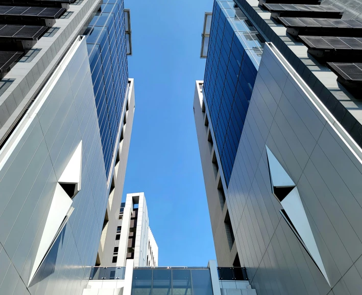 two tall buildings are viewed upward from below