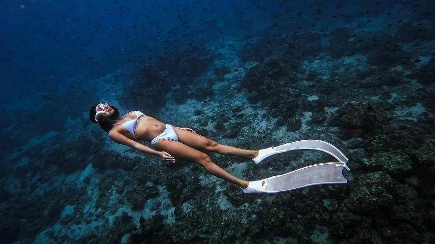 a woman snoraks over some coral on the ocean floor