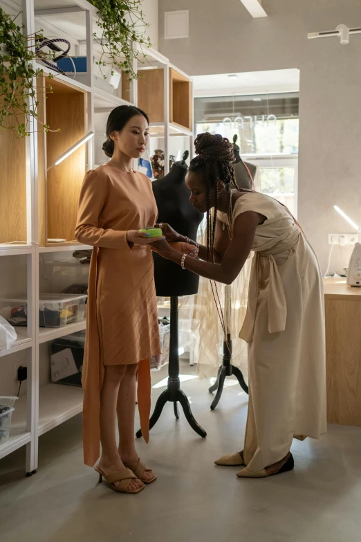 two women looking at a purse that is on a mannequin