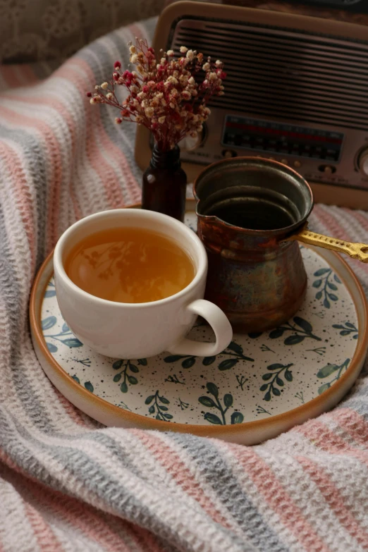 a cup of tea on a plate next to a radio