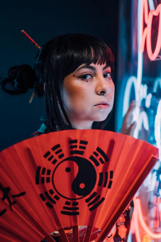 a woman is holding a chinese fan in front of her face