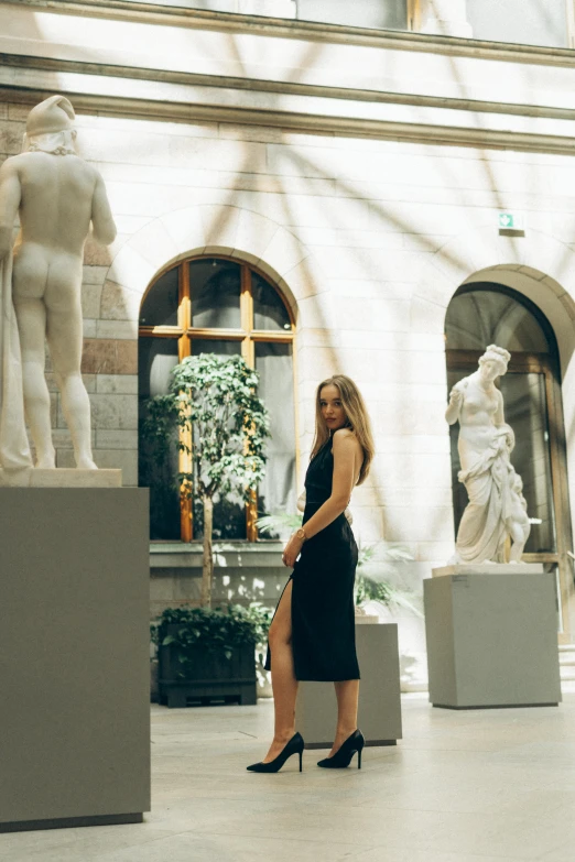 a beautiful woman standing in front of some white statues