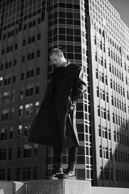 a man in black clothing stands by a tall building