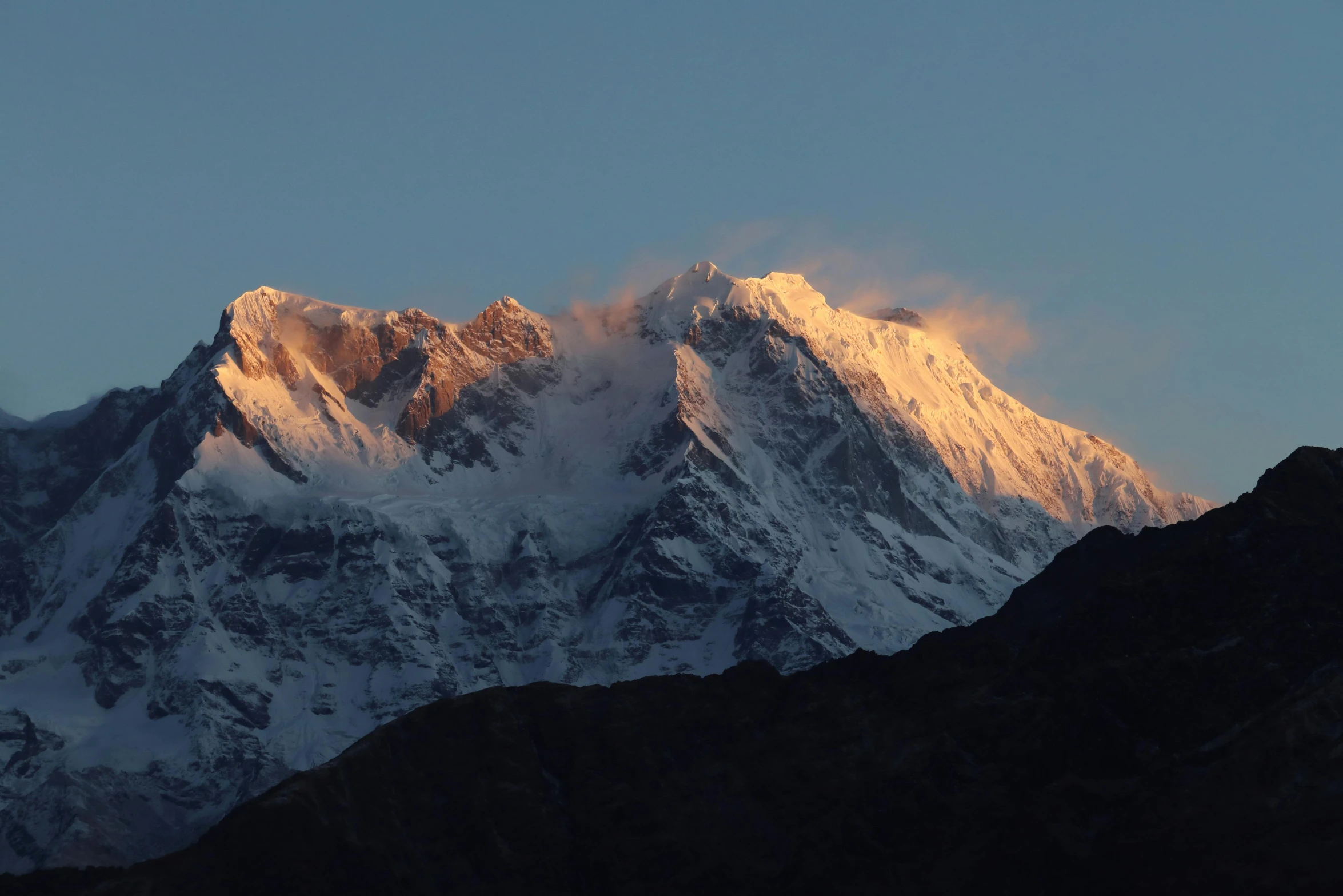 a large snow covered mountain is seen during sunset