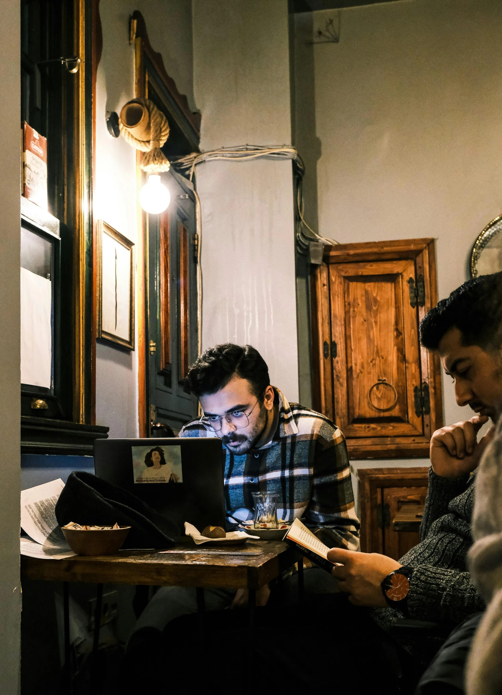 a group of three people sit at a table working on laptops