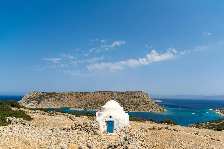 a white building sitting on top of a hillside near water