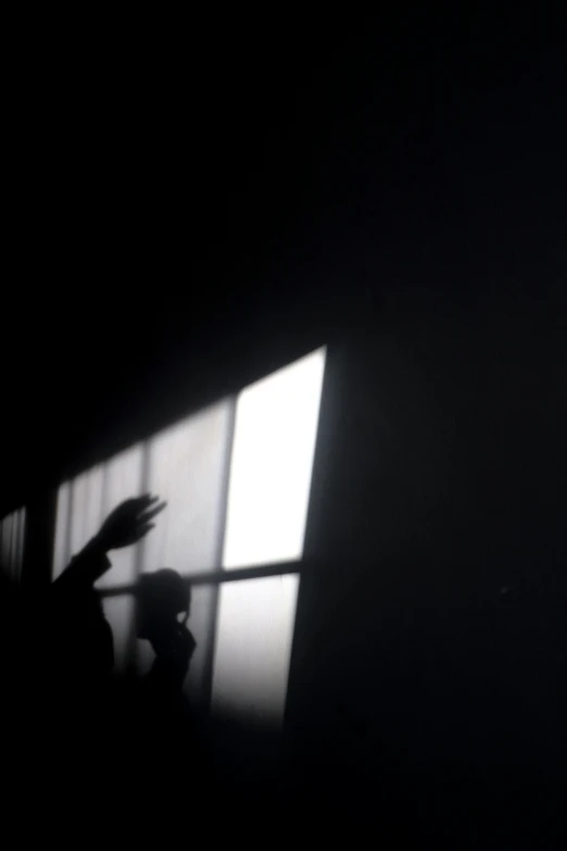 a dark room with a large window and a hand reaching out