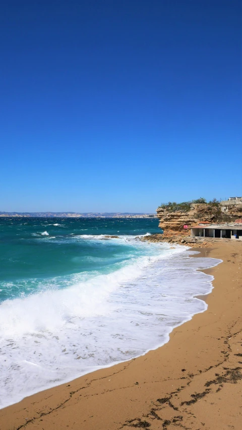 an empty beach has white water and blue sky