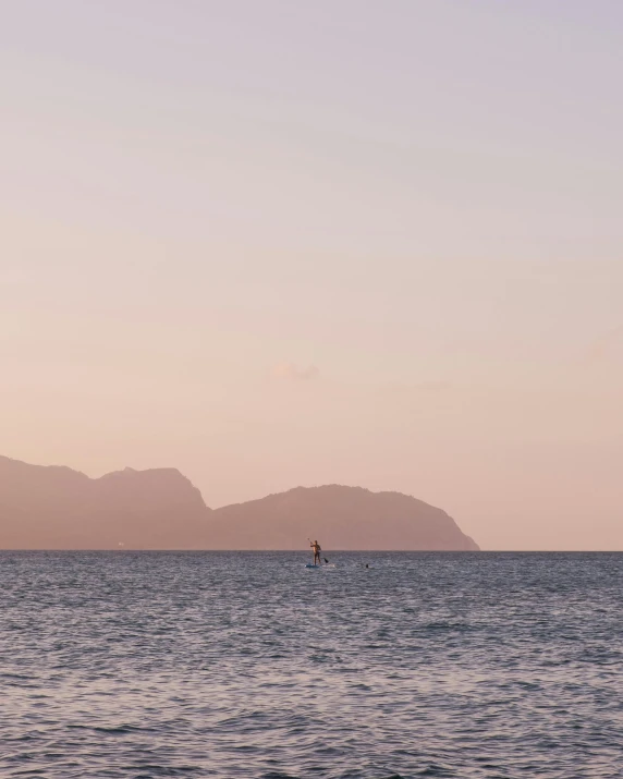 a person is sailing in the water with mountains behind them