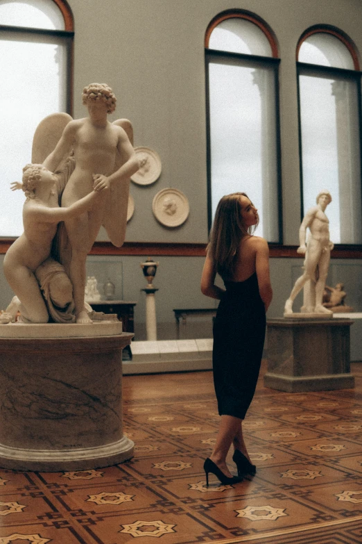 a woman in black dress looking at statues