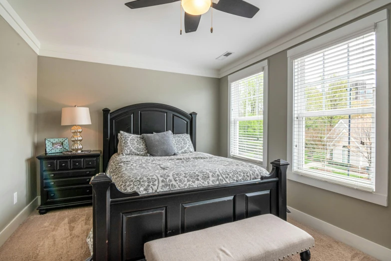 a bedroom with large bed and two windows