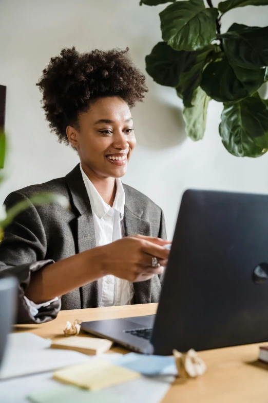 woman smiling while sitting in front of laptop computer