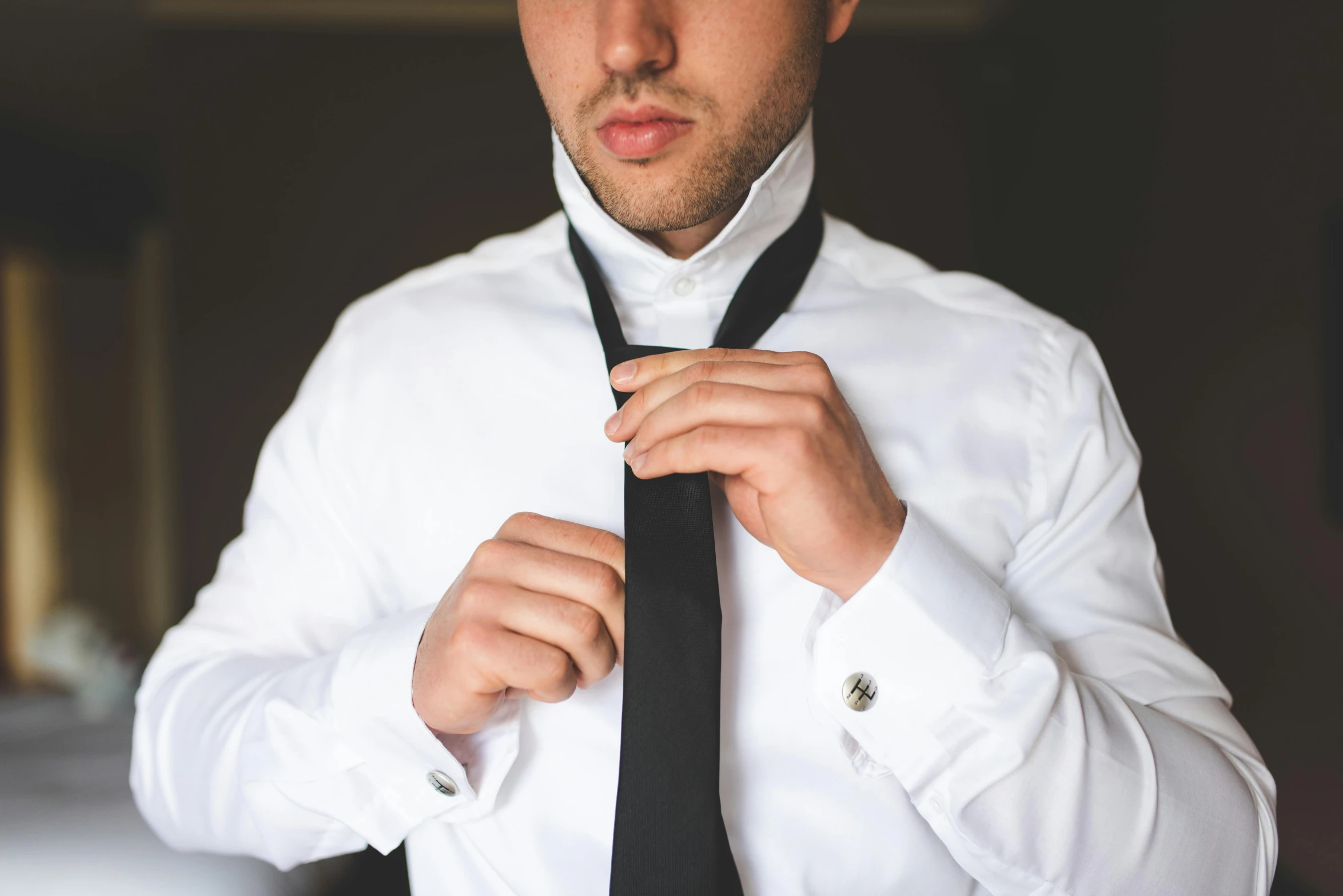 the man is fixing his tie while wearing a white shirt and black tie