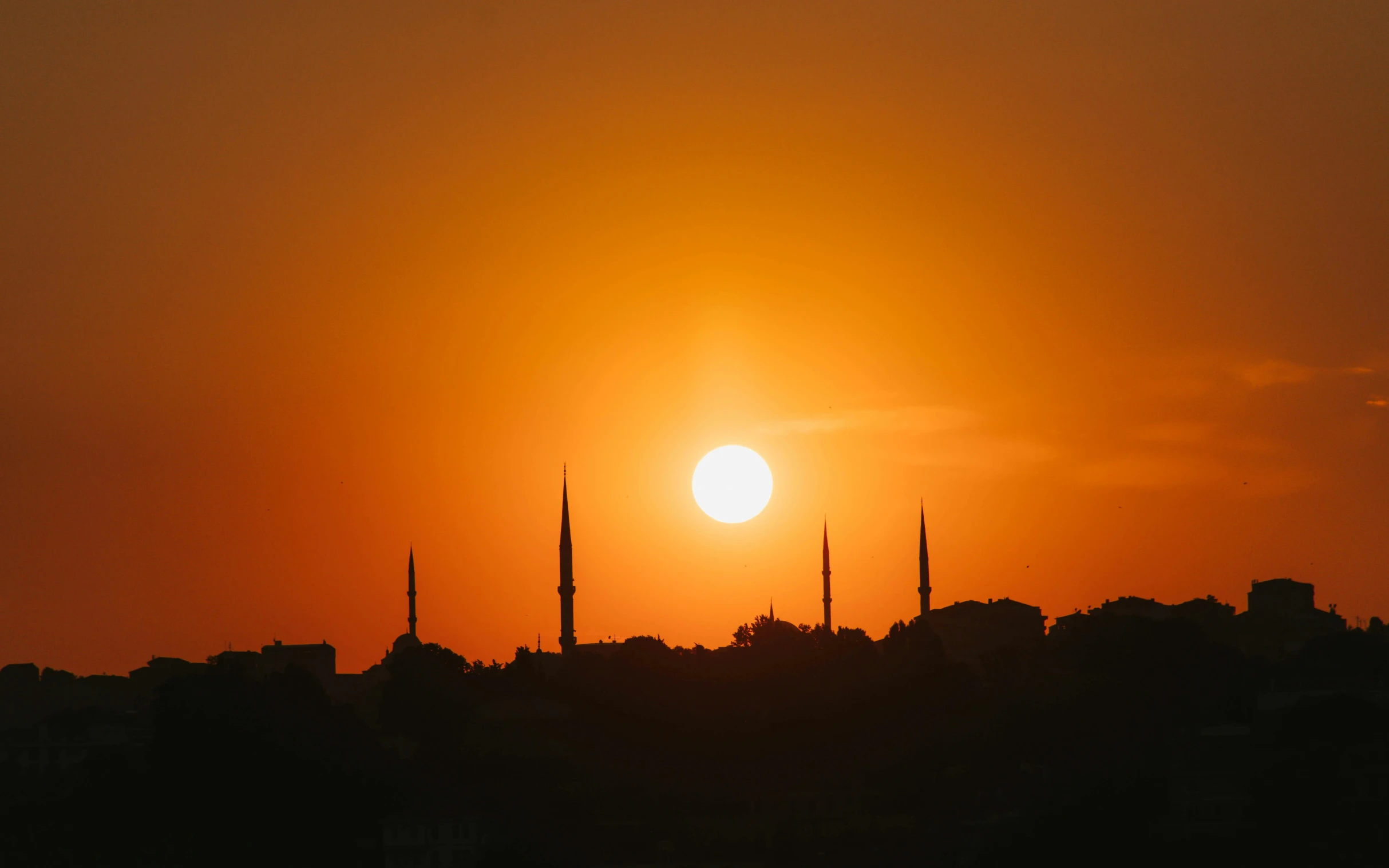 a cityscape that has the sun setting with the silhouette of tall buildings in the background