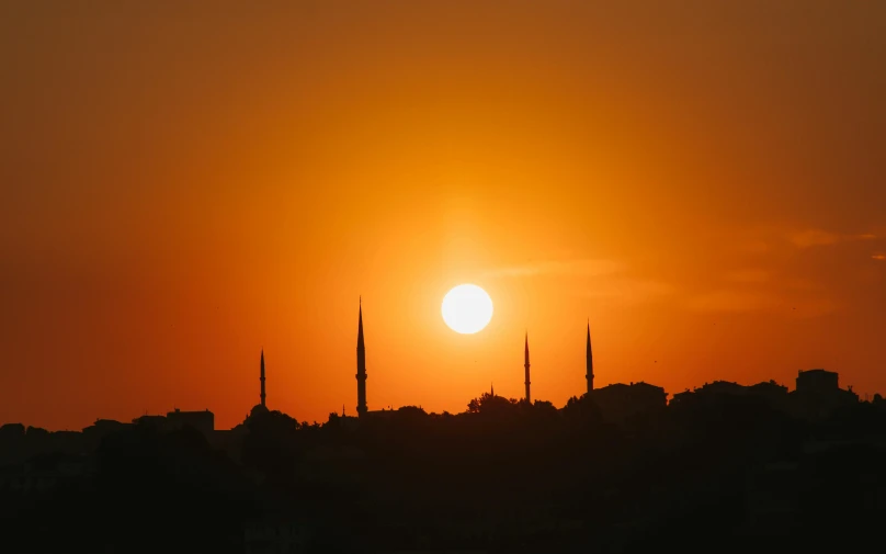 a cityscape that has the sun setting with the silhouette of tall buildings in the background