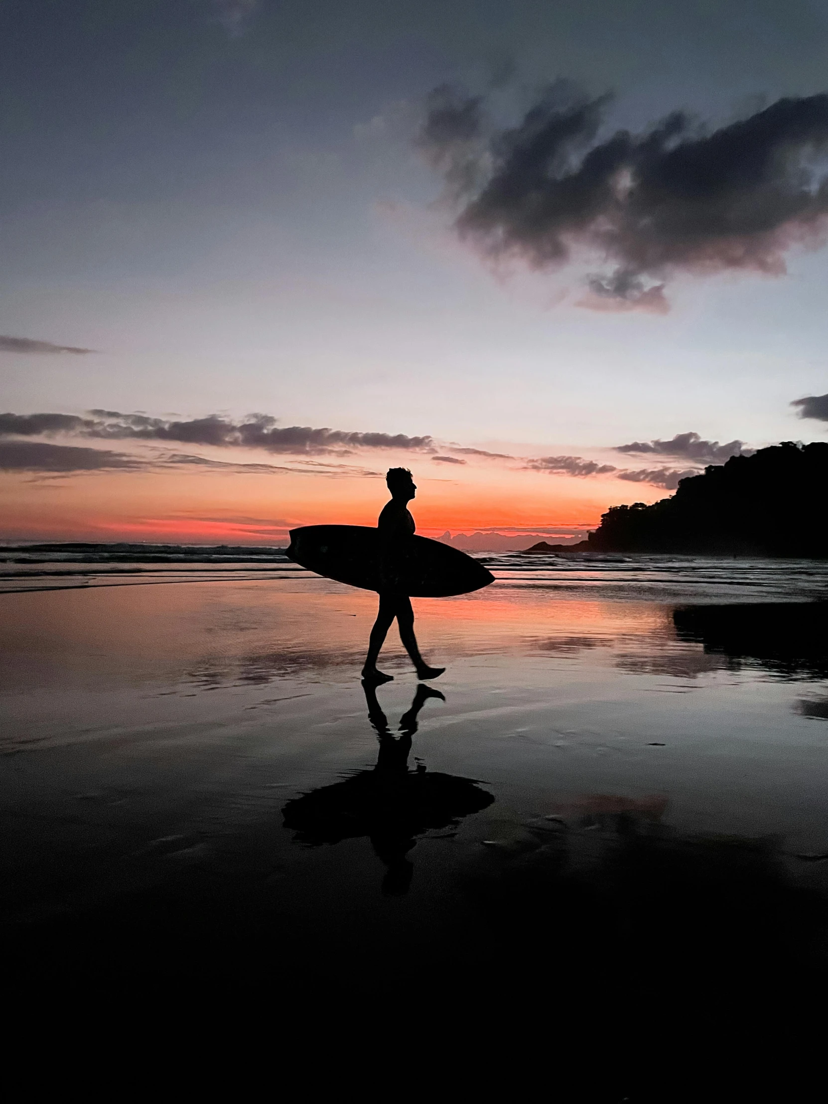 a man holding a surf board walking along a beach