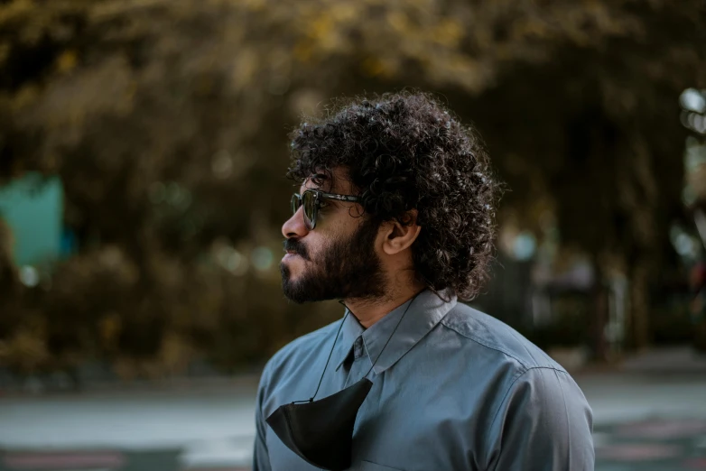 a man with curly hair and sunglasses walking