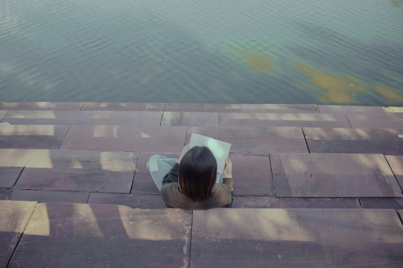 the woman is sitting on a brick floor outside and her umbrella looks on