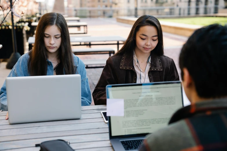 a group of people sitting at tables with laptops