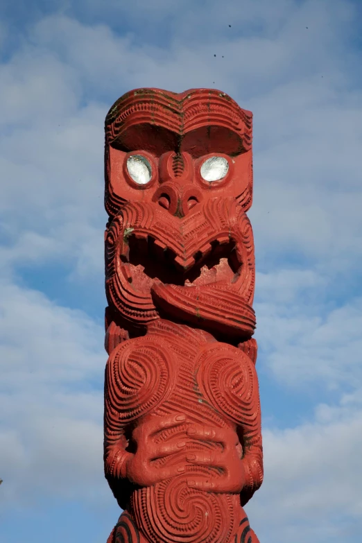 an ancient statue with big eyes is painted red