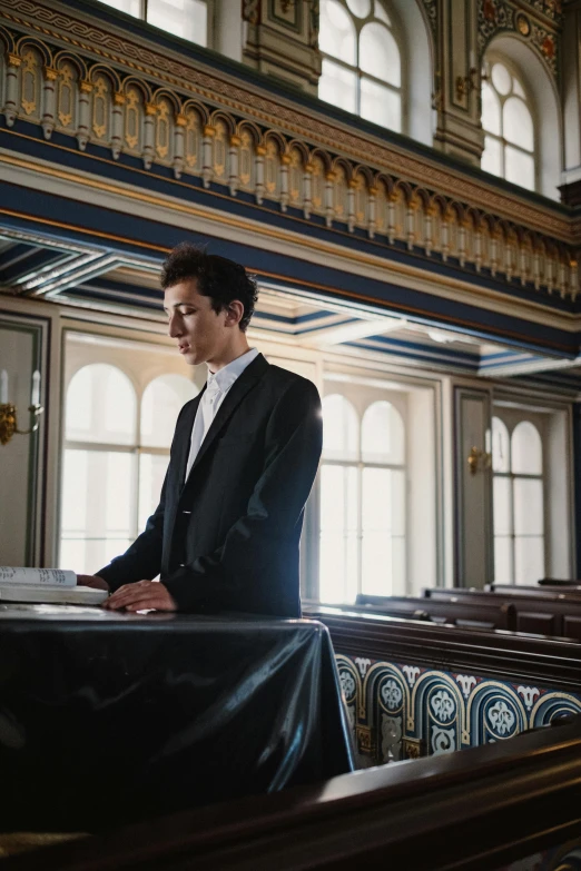 the man in a black suit is looking at a book