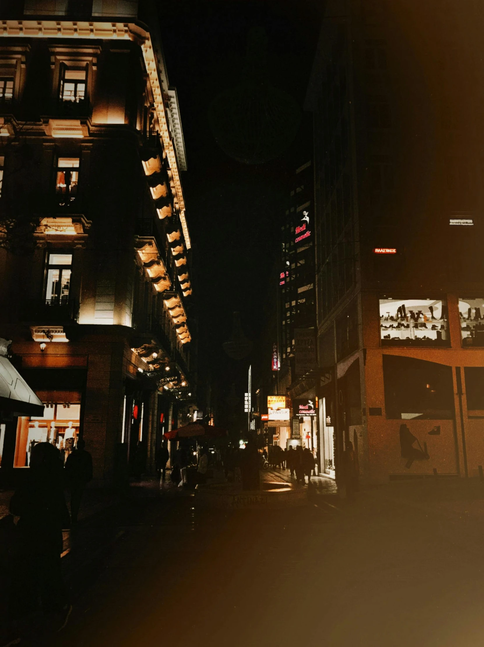 a dark city with lit up buildings and people walking